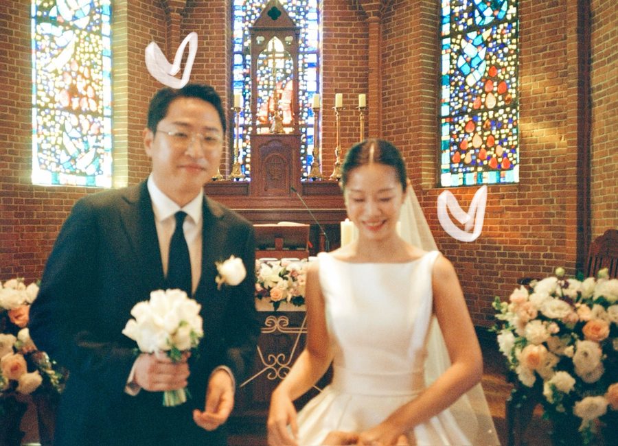 스테인드글라스 아래에서 웃으며 서 있는 신랑 신부