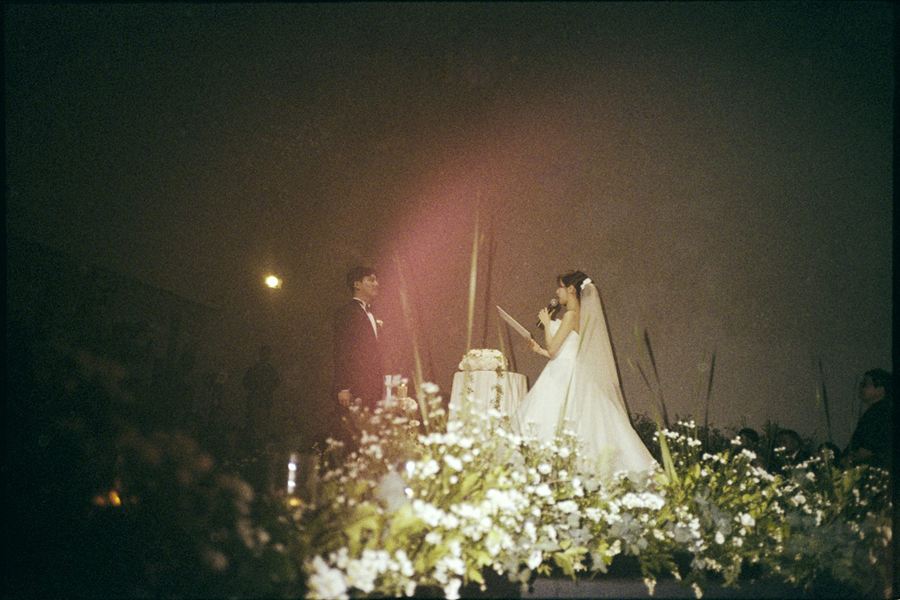 은은한 조명 속 꽃길 위의 신랑 신부